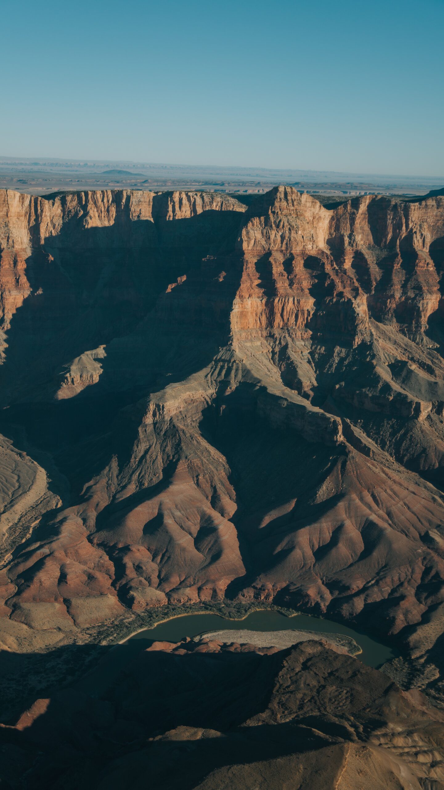 Aerial view of the Grand Canyon showing layered red rock strata and the Colorado River winding through the canyon floor