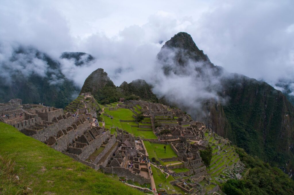 Aerial view of Machu Picchu's ruins wrapped in mist with green mountains behind them
