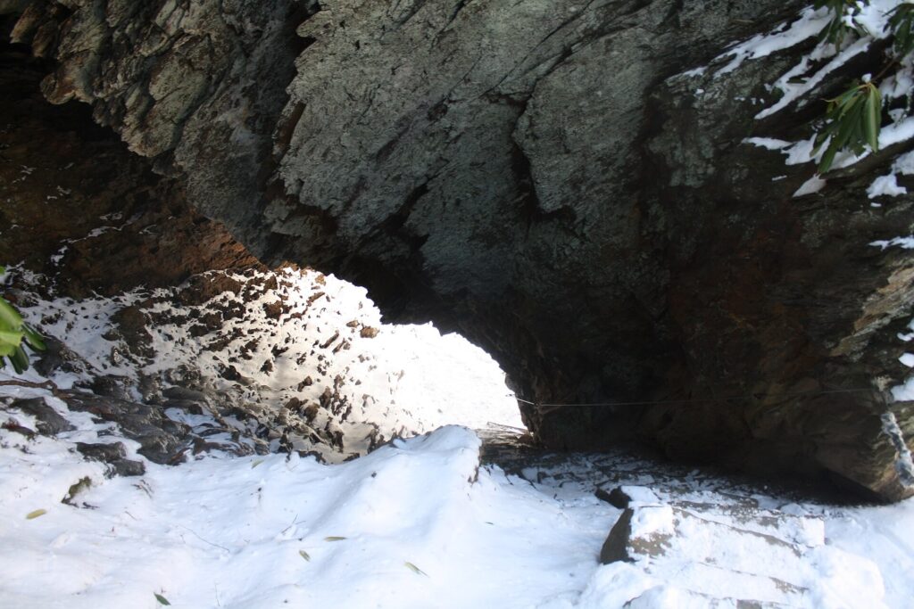Stone steps climbing through Arch Rock on the Alum Cave Trail, dusted with snow
