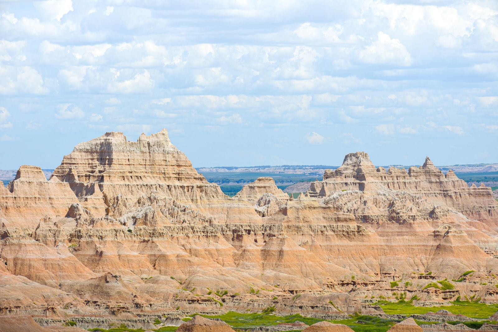 Layered rock formations at Badlands National Park under a partly cloudy sky
