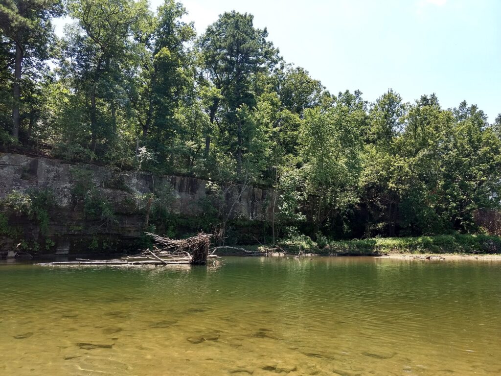 The Big Piney River flowing past a wooded, rocky bluff in the Missouri Ozarks