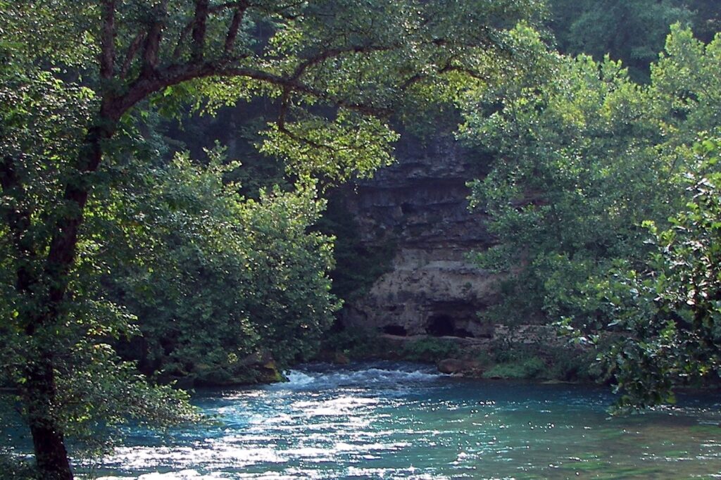 Big Spring's blue water emerging at the base of a wooded bluff near Van Buren, Missouri