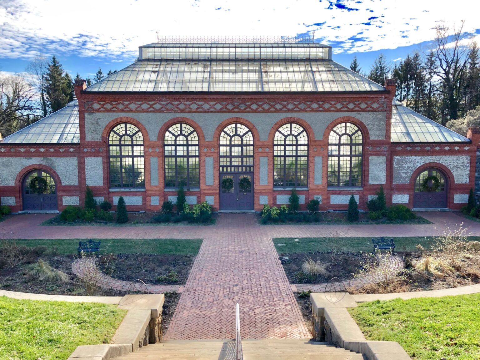 The brick and glass Conservatory at the foot of the Walled Garden at Biltmore Estate, with a brick path leading to its arched doors