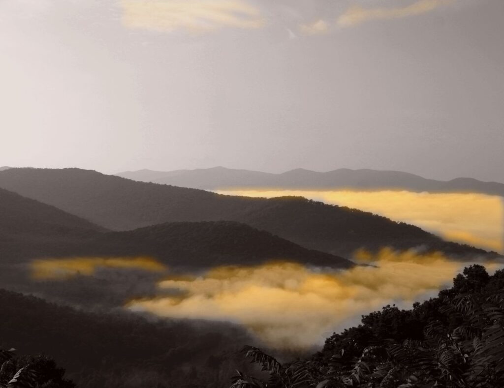 Layered mountain ridges and fog lit by sunset at an overlook on the Blue Ridge Parkway near Asheville