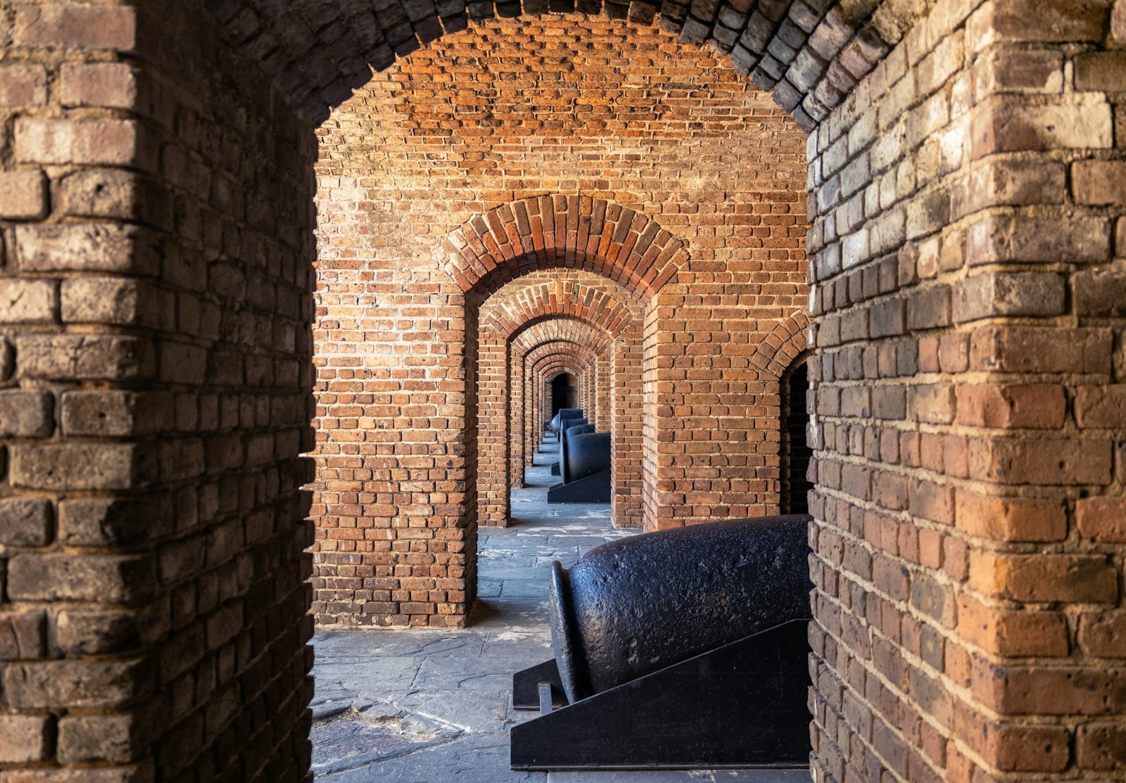 A brick corridor lined with old cannons inside the historic fort at Fort Zachary Taylor in Key West