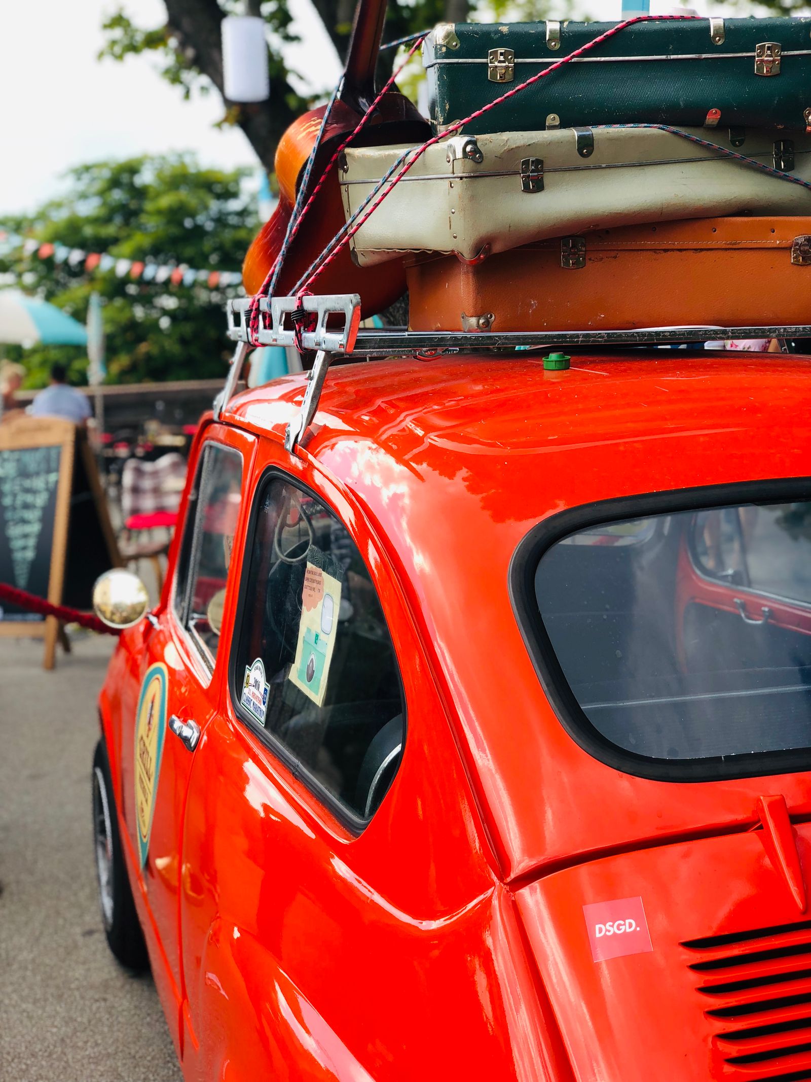 A car with a suitcase packed and strapped to the roof rack, ready for a road trip