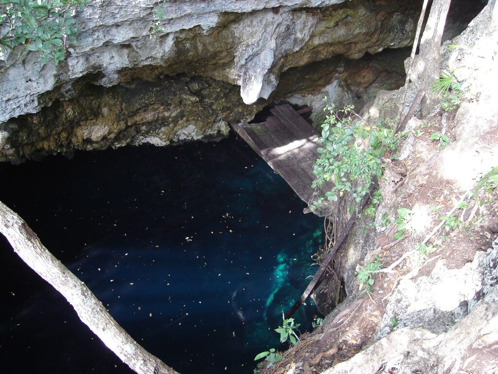 A diver swims through a beam of light inside an underwater cenote cave in the Yucatan