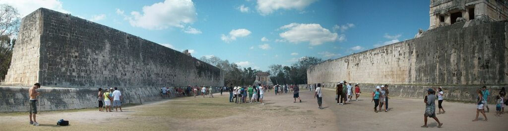 Panoramic view of the Great Ball Court at Chichen Itza, flanked by stone walls
