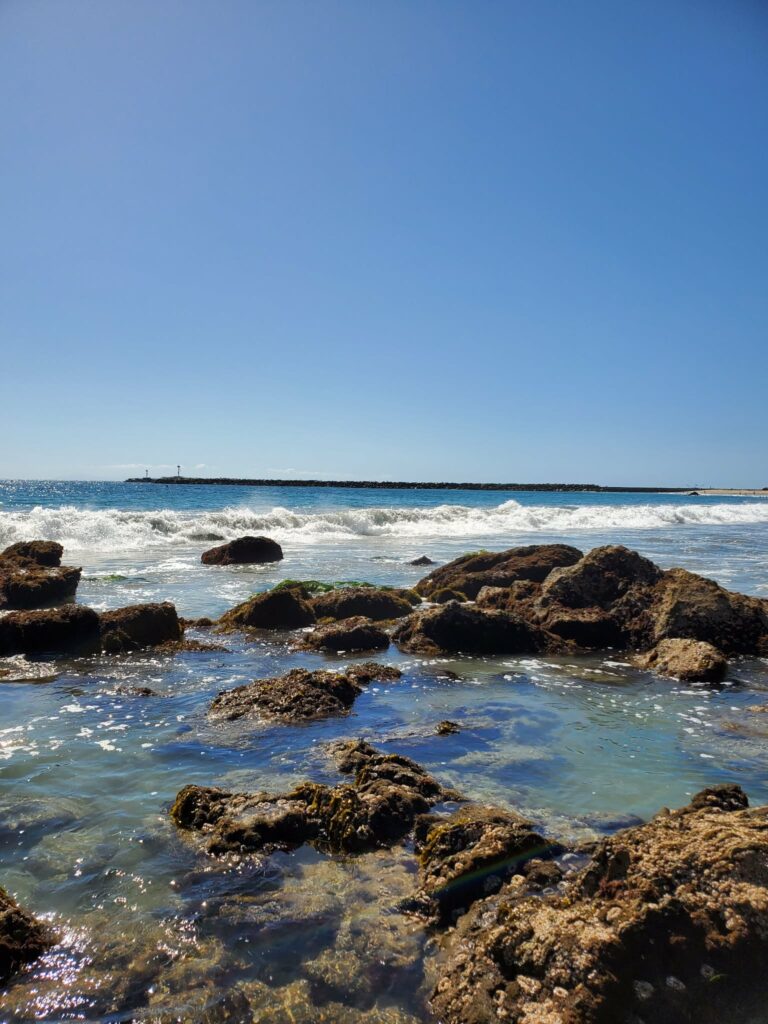 Tide-pool rocks with the Newport Harbor jetty behind them at Corona del Mar