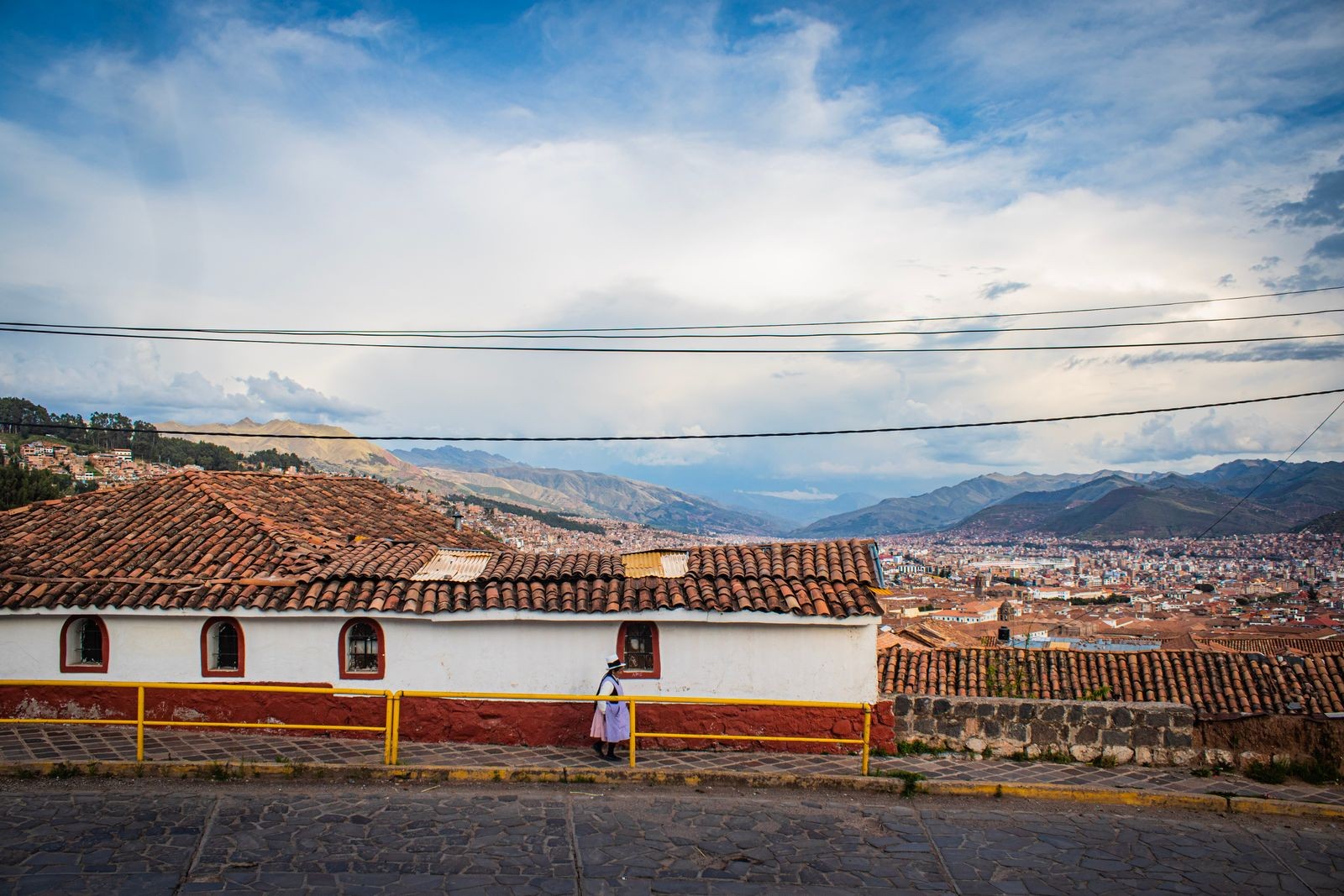 Terracotta rooftops of Cusco with the surrounding mountains and city visible behind