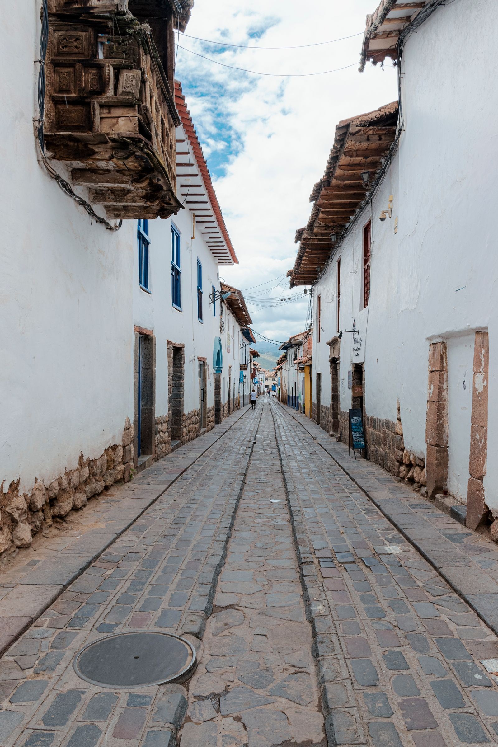 A narrow cobblestone street lined with whitewashed buildings in Cusco, Peru
