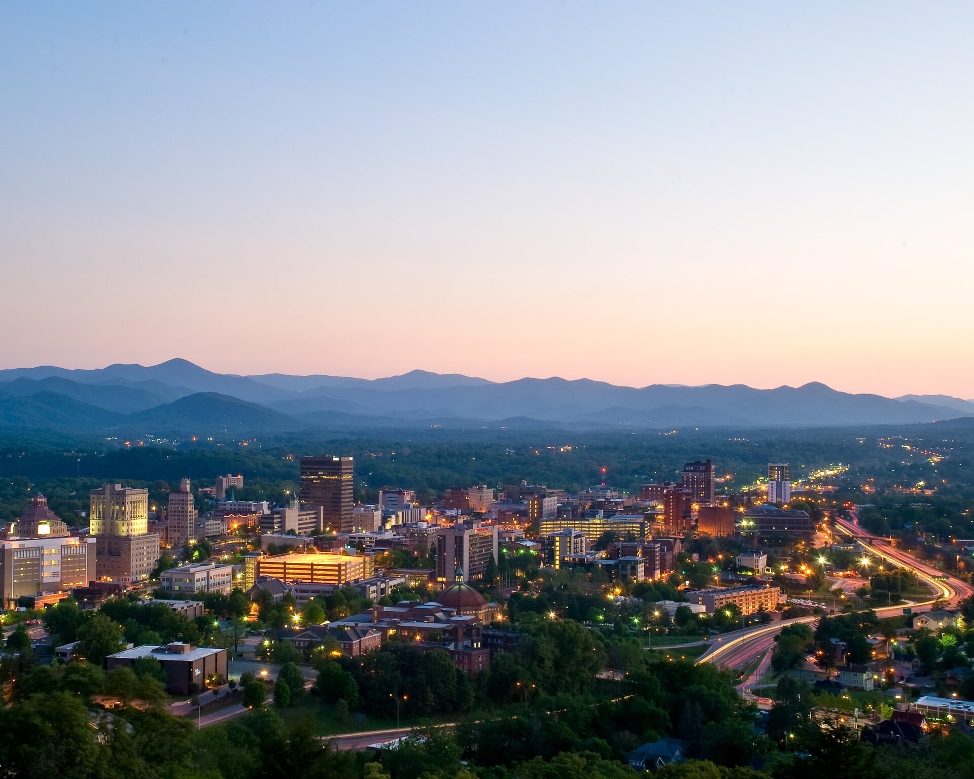 Downtown Asheville, North Carolina, at dusk with the Blue Ridge Mountains behind