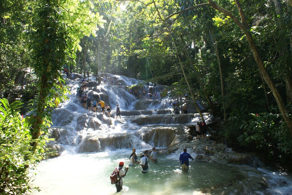 Tourists climbing Dunn's River Falls in a human chain, holding hands as they move up the wet rock