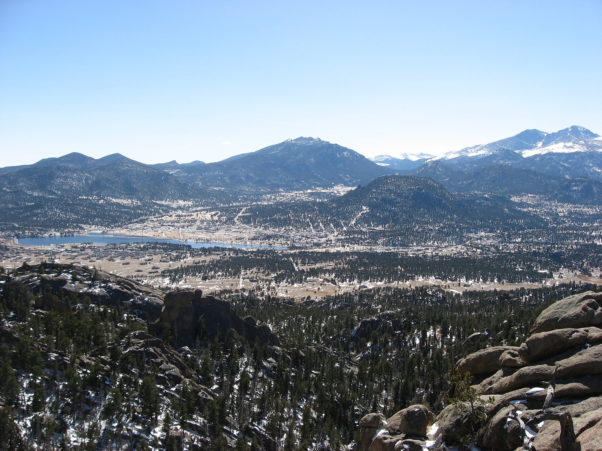 The town of Estes Park, Colorado seen from a high overlook with mountains behind it