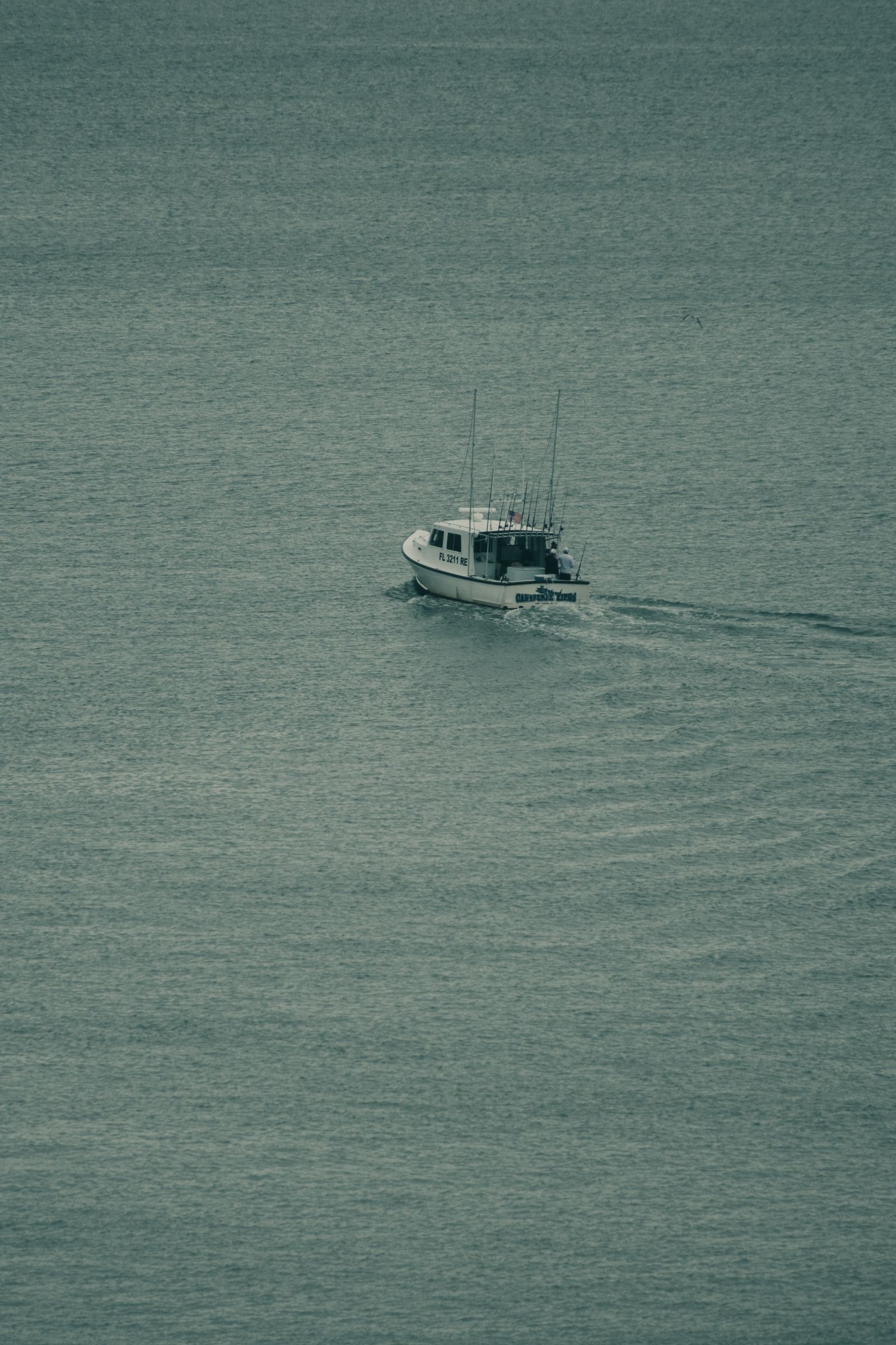 A single fishing boat moving across calm, open water.