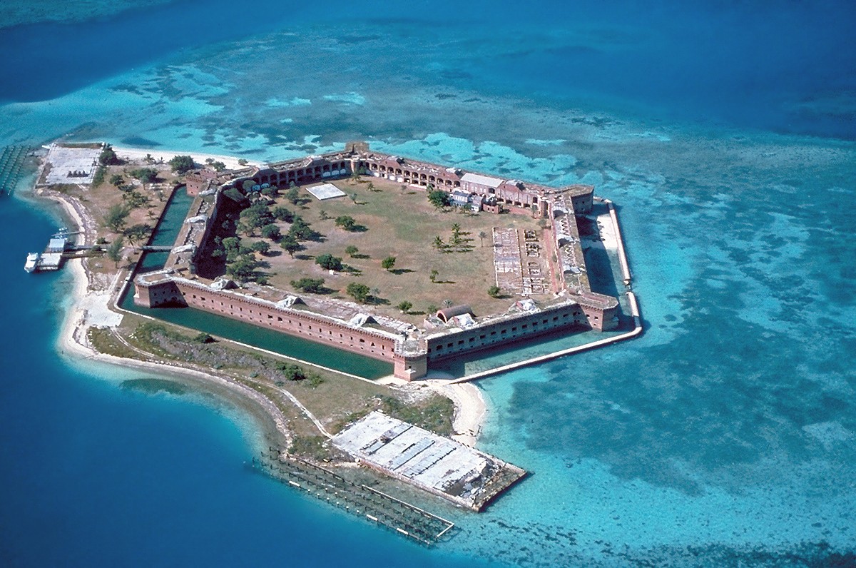 Fort Jefferson from the air: a six-sided brick fort filling almost all of Garden Key, ringed by its moat wall and pale reef flats