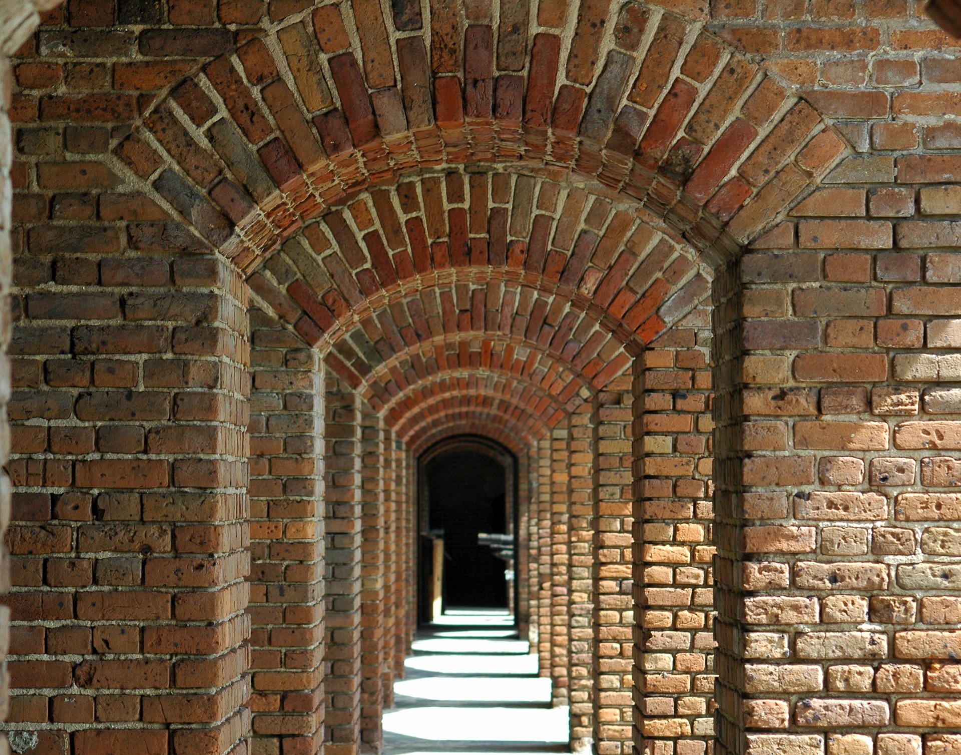 A long gallery of brick arches inside Fort Zachary Taylor, Key West, with sunlight falling through the openings on one side