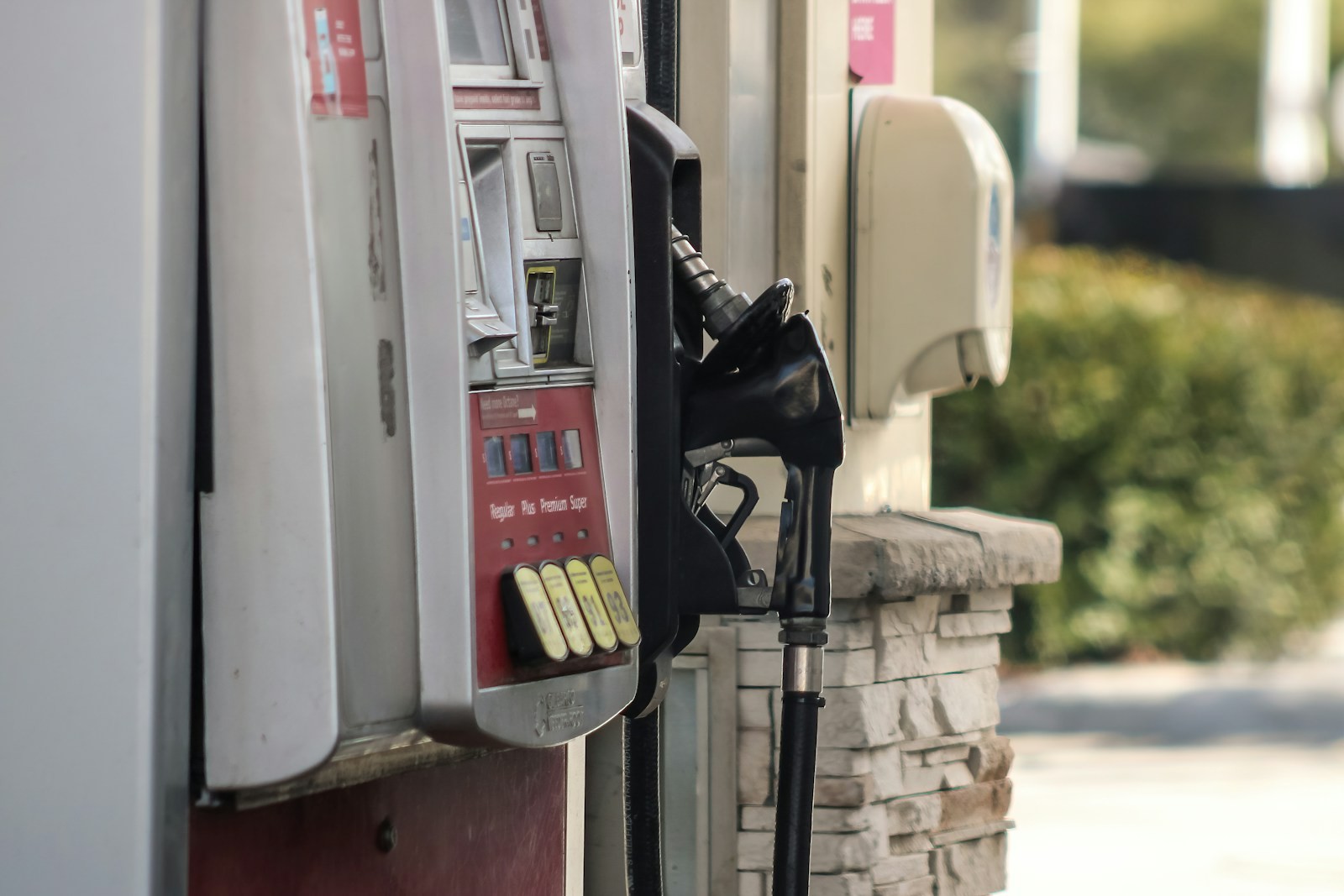 A fuel pump standing beside a brick wall.