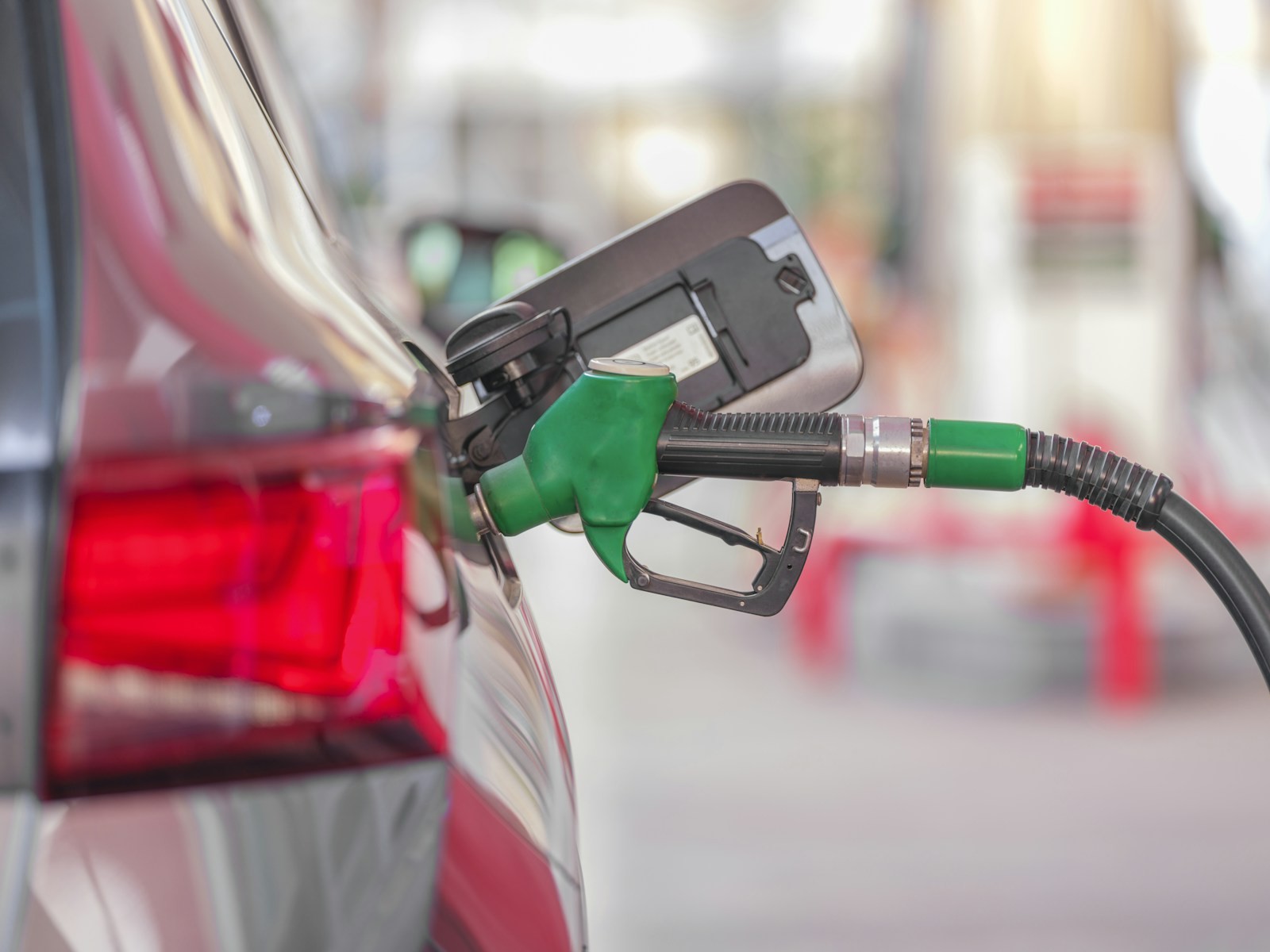 A fuel pump nozzle connected to a car at a filling station.