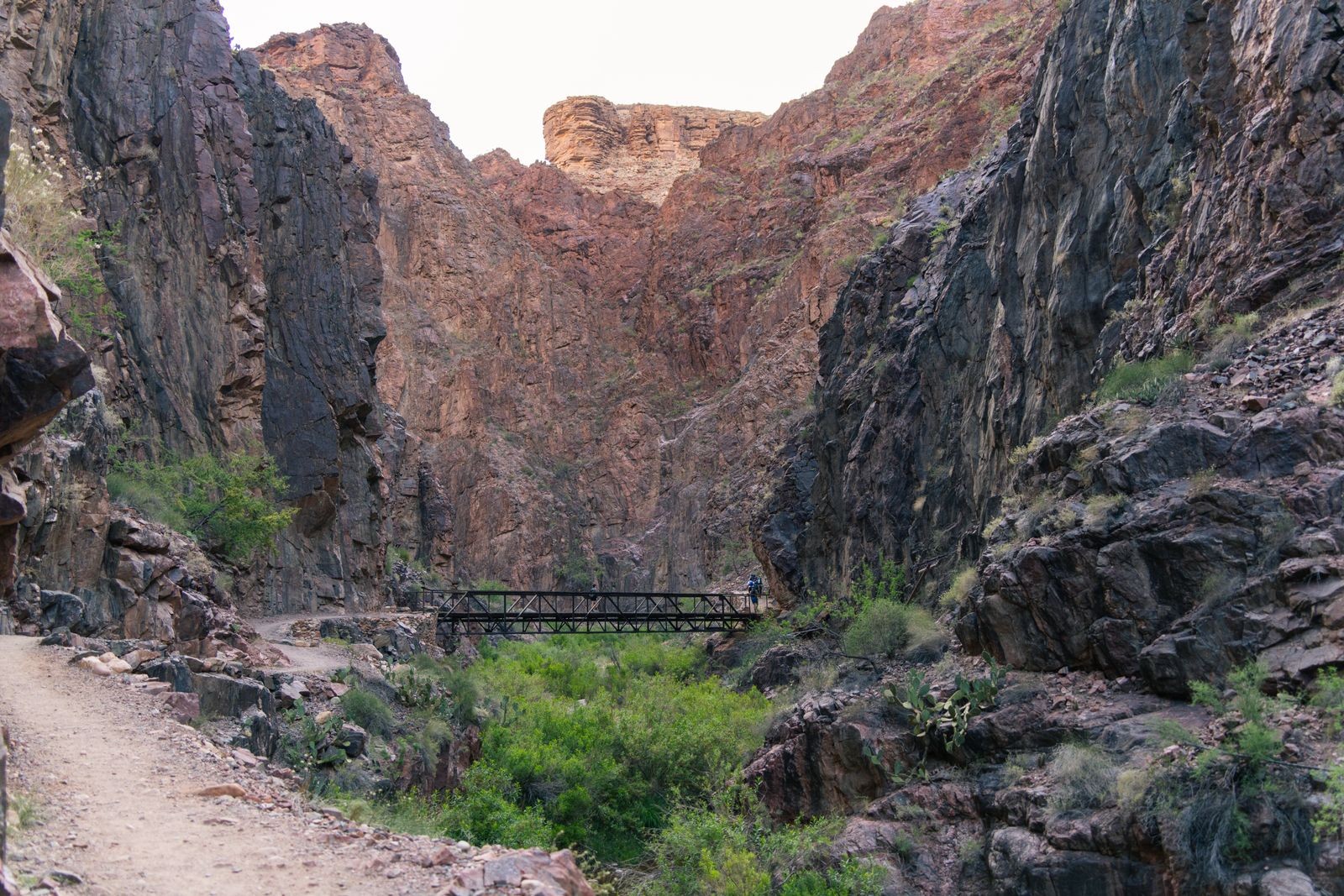 A footbridge crosses a rocky inner-canyon trail near the bottom of the Grand Canyon