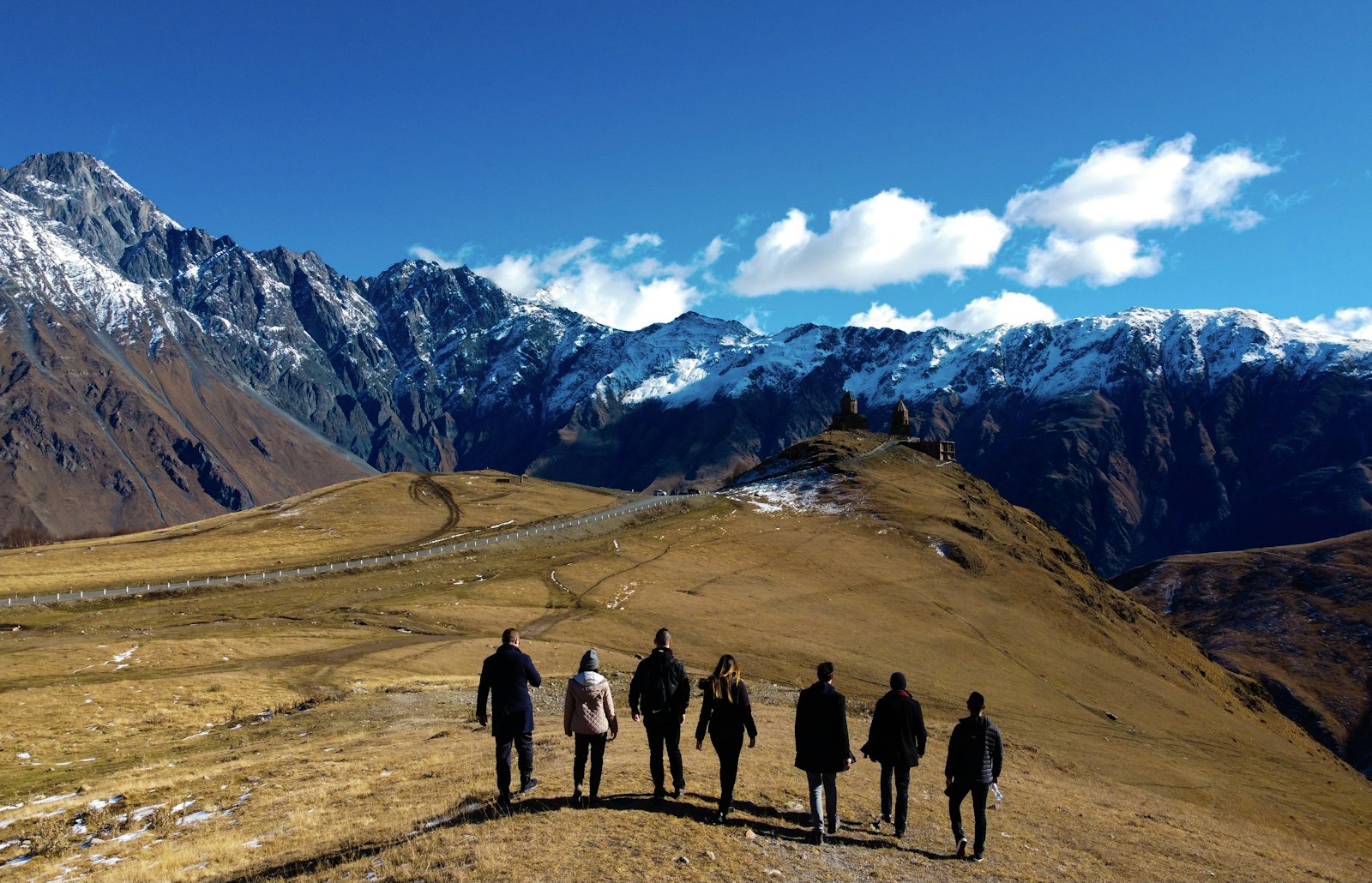 Group of travelers with backpacks hiking near a mountain
