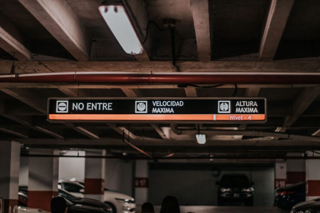 Interior of a parking garage with overhead signage showing vehicle height and speed limits