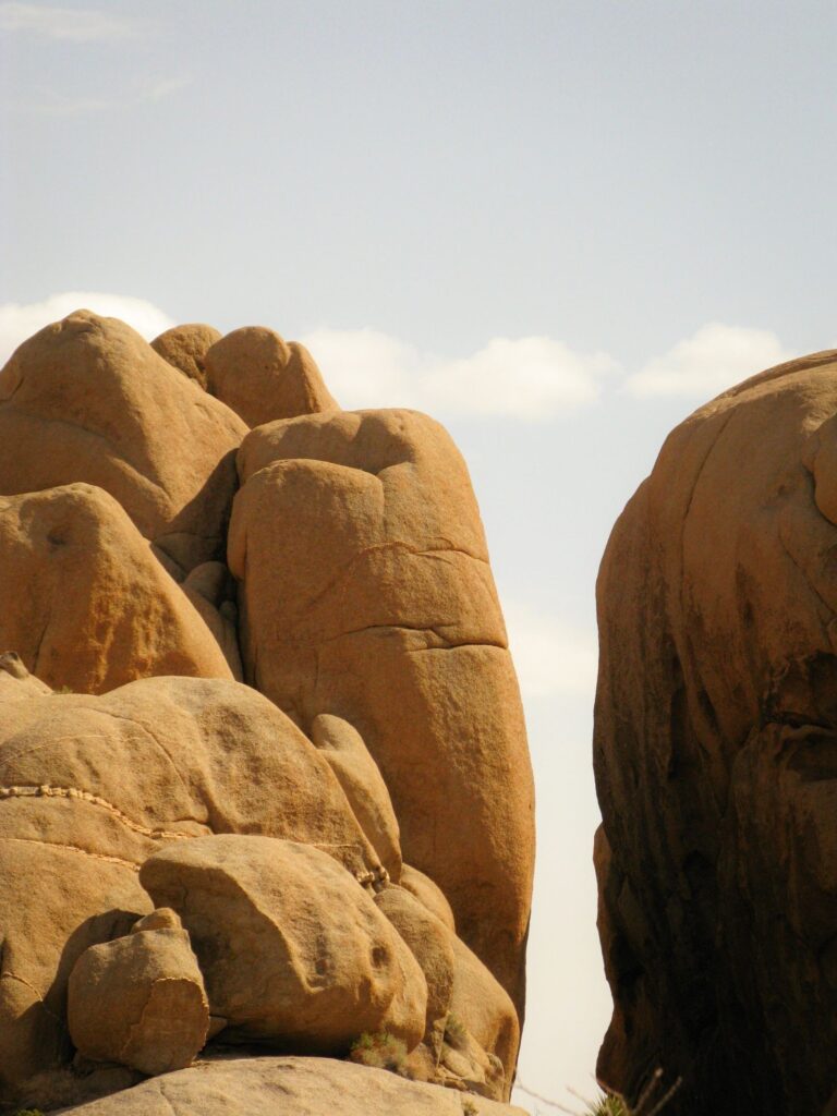Weathered boulder formations stacked against a bright desert sky in Joshua Tree National Park