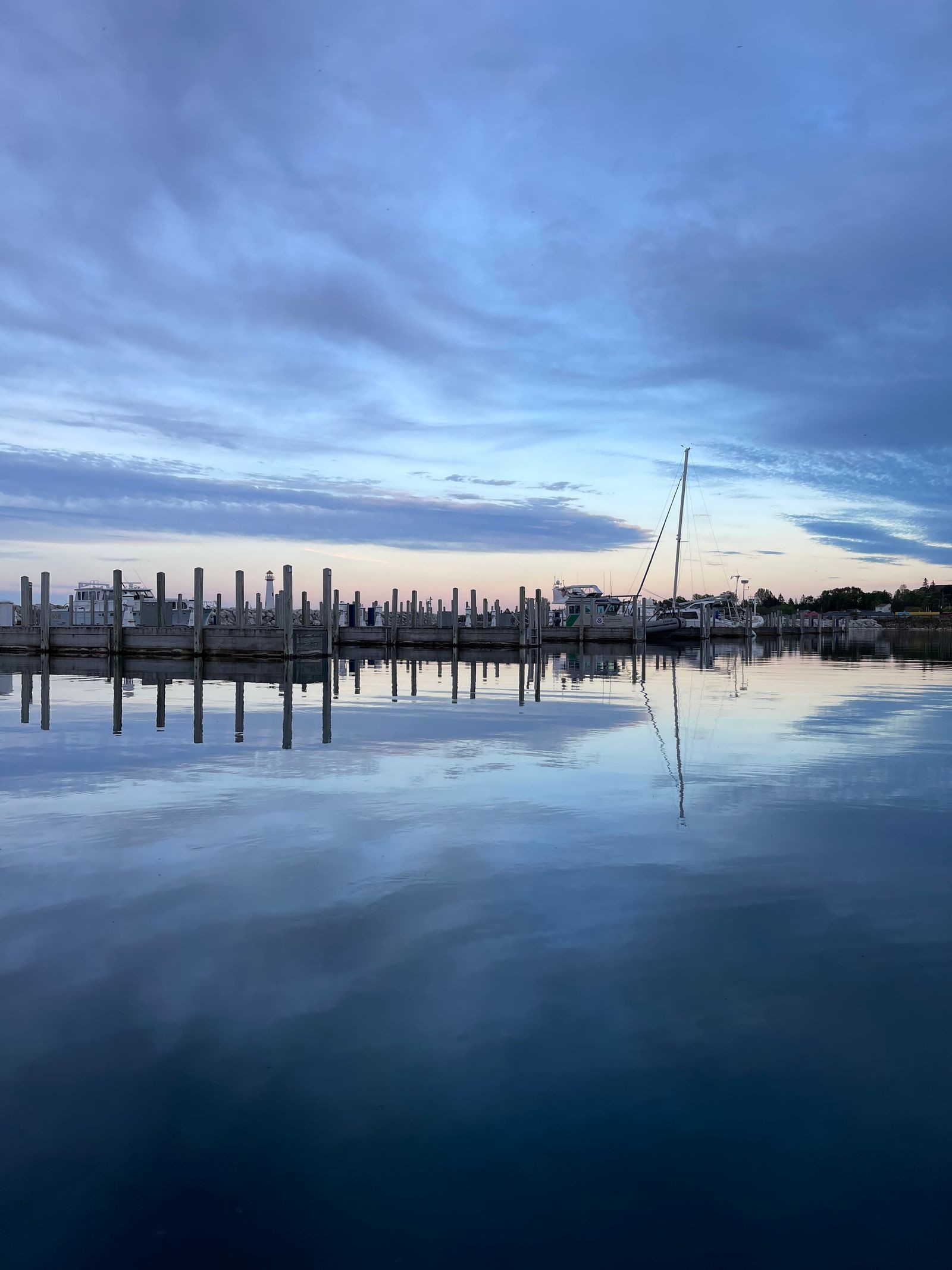 Mackinac Island harbor at dusk with empty dock pilings reflected in flat water