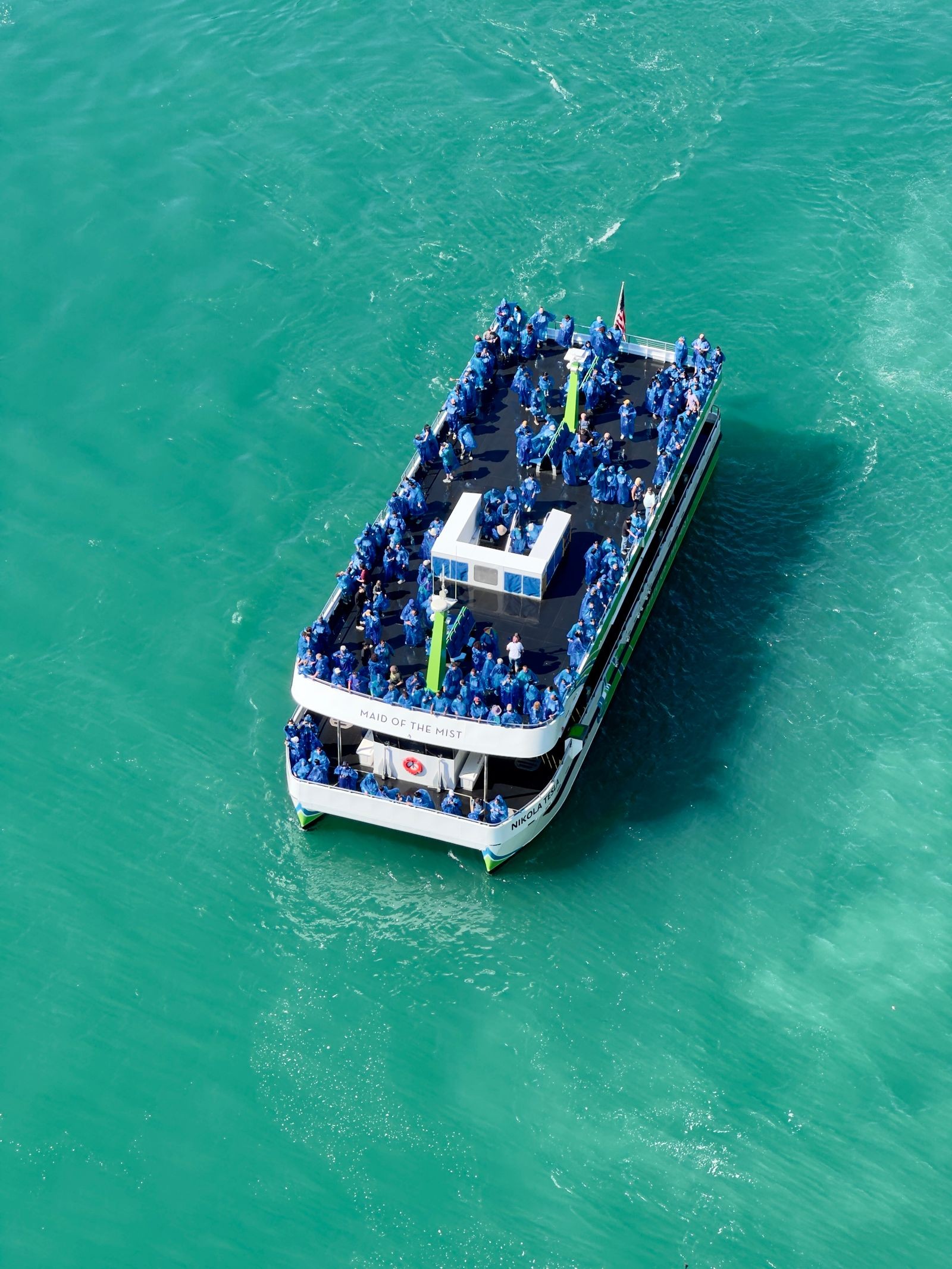 The Maid of the Mist tour boat carrying passengers in blue ponchos near the falls