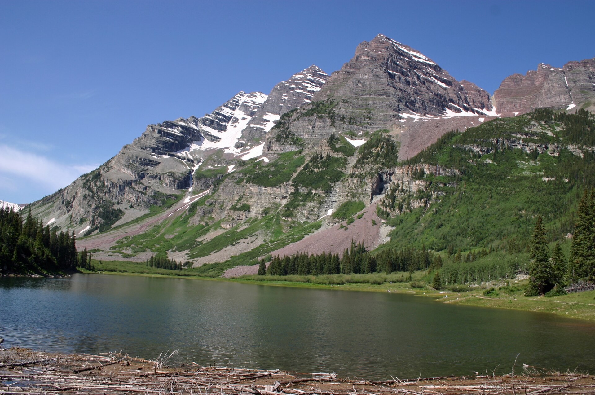 The Maroon Bells peaks reflected in Maroon Lake near Aspen, Colorado, with evergreens along the shore