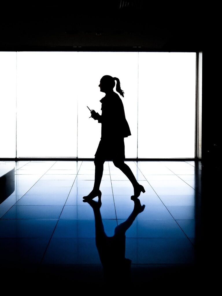 A traveler silhouetted while walking through an airport terminal corridor