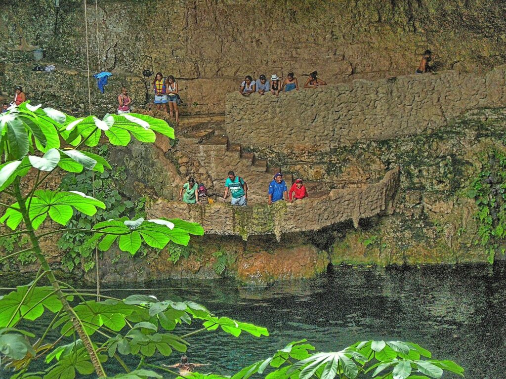 A cenote sinkhole with rock walls and stairs down to the water near Valladolid, Yucatan