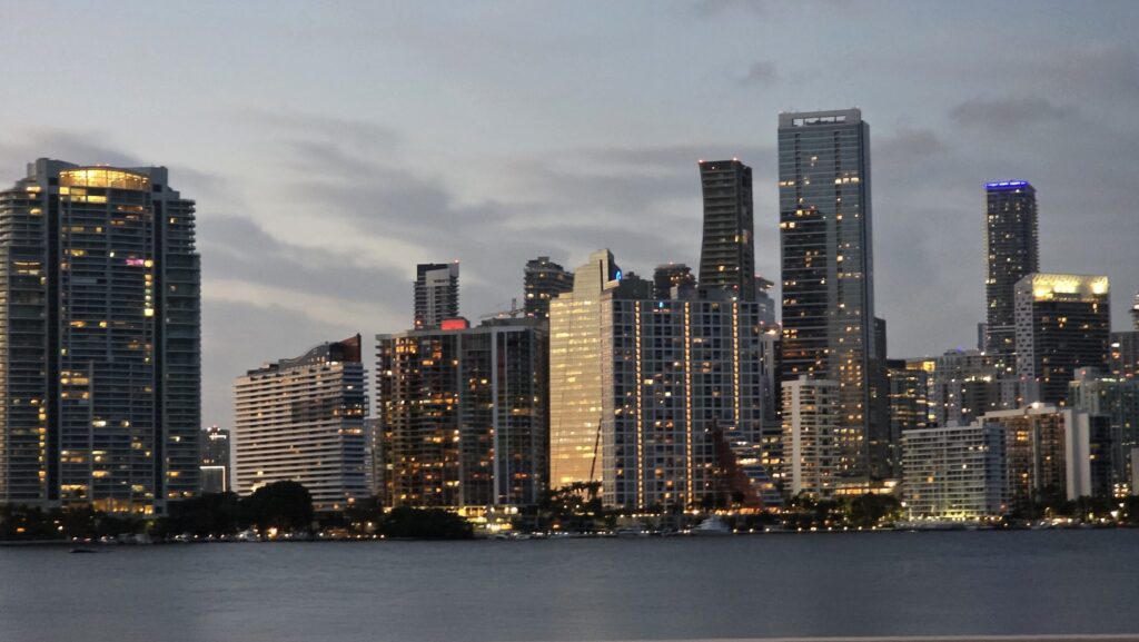Brickell skyline at dusk from Biscayne Bay, towers lit against a cloudy sky