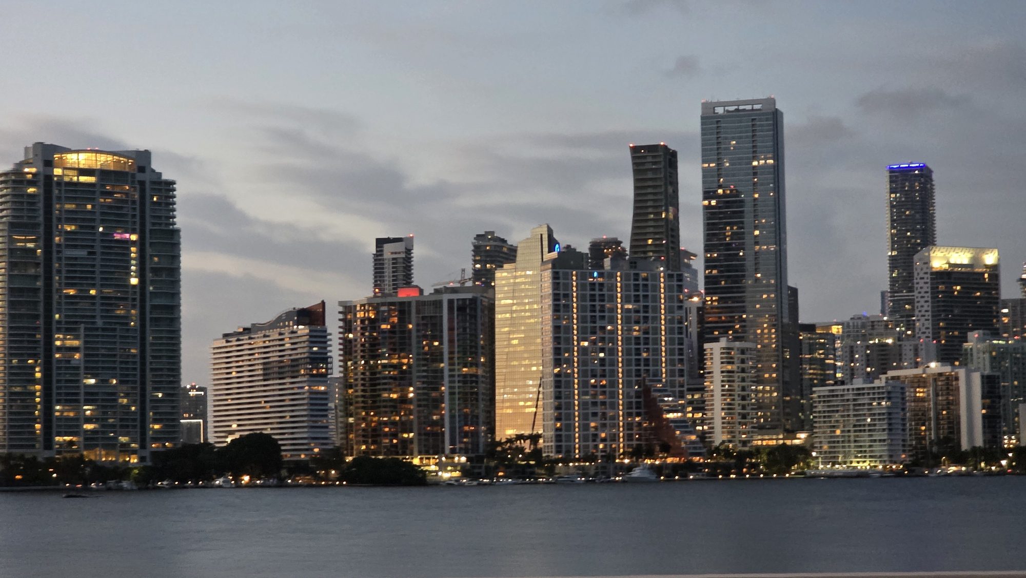 Brickell skyline at dusk from Biscayne Bay, towers lit against a cloudy sky