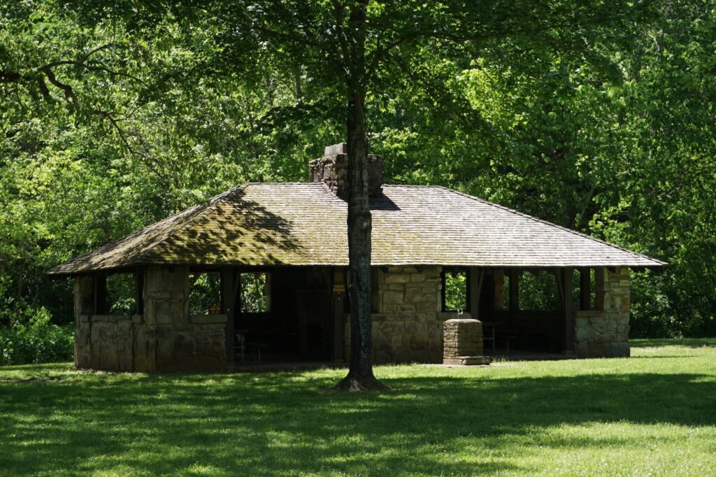 An open stone picnic shelter under trees at Montauk State Park