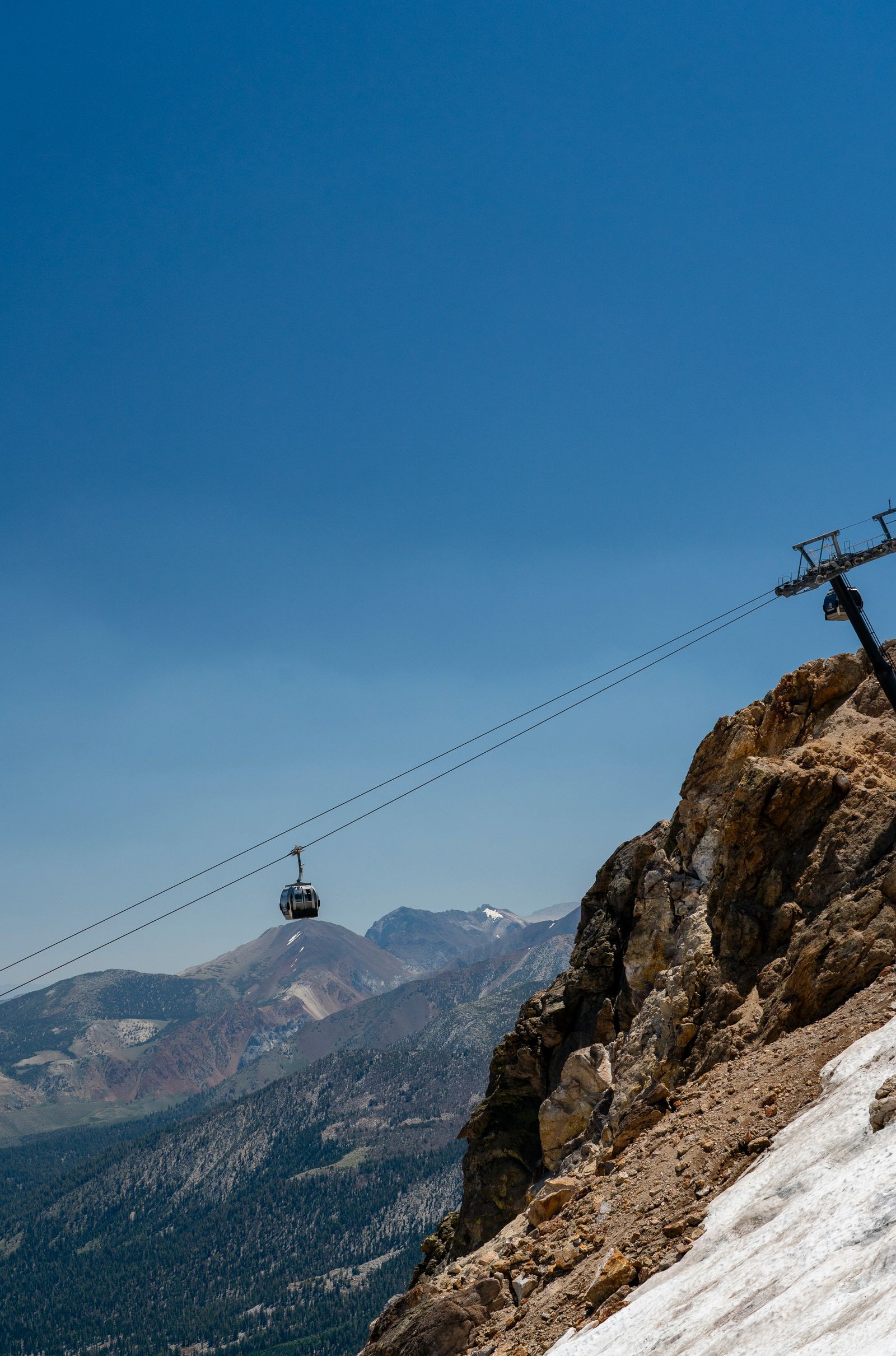 A cable car climbs a steep, rocky mountainside