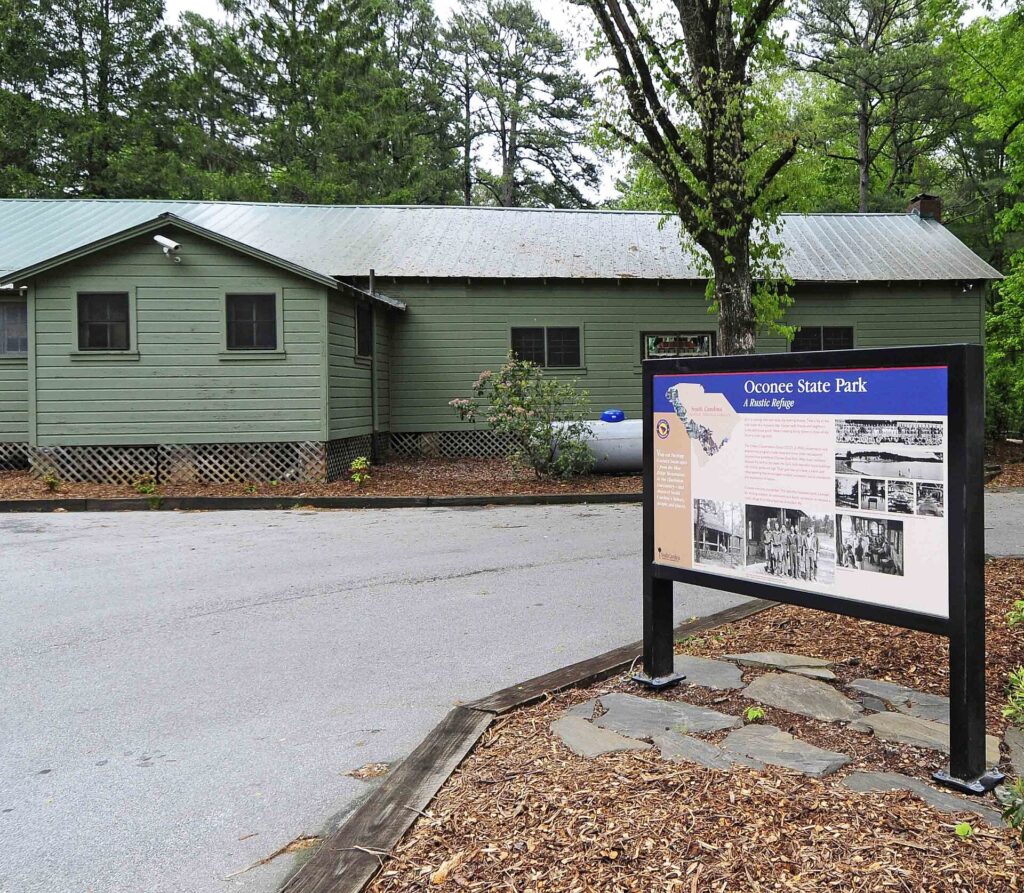 Green CCC-era cabin and information sign in the Oconee State Park Historic District, South Carolina
