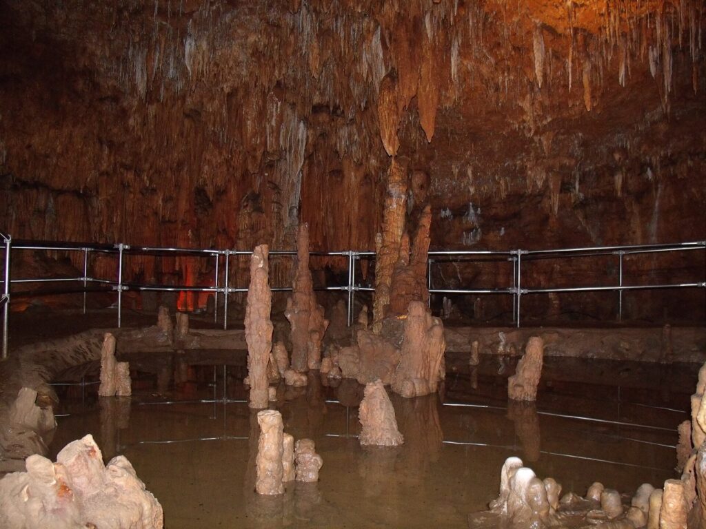 Lit rock formations and a walkway railing inside Onondaga Cave, Missouri