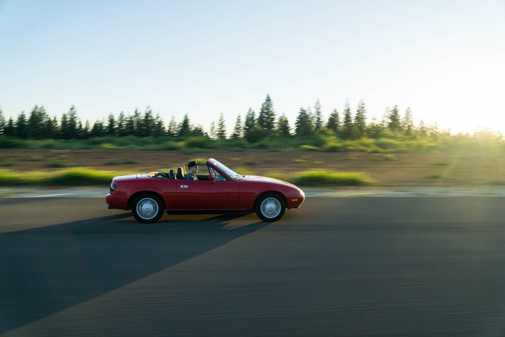 A red convertible driving along an open highway.