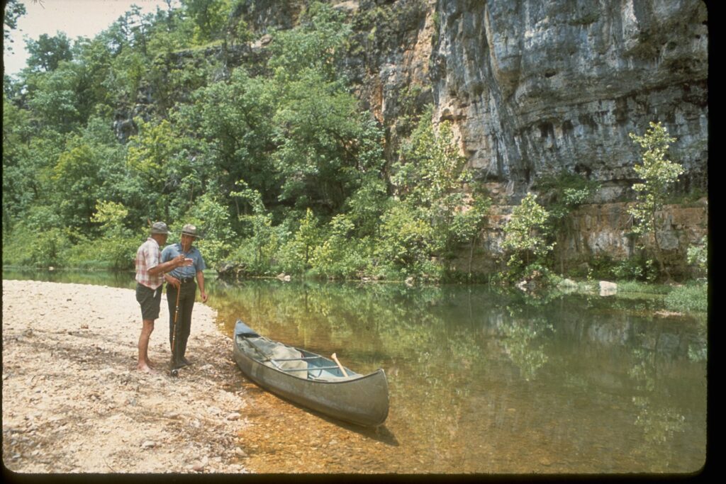 Canoeists take a break on a gravel bar along a limestone bluff within Ozark National Scenic Riverways