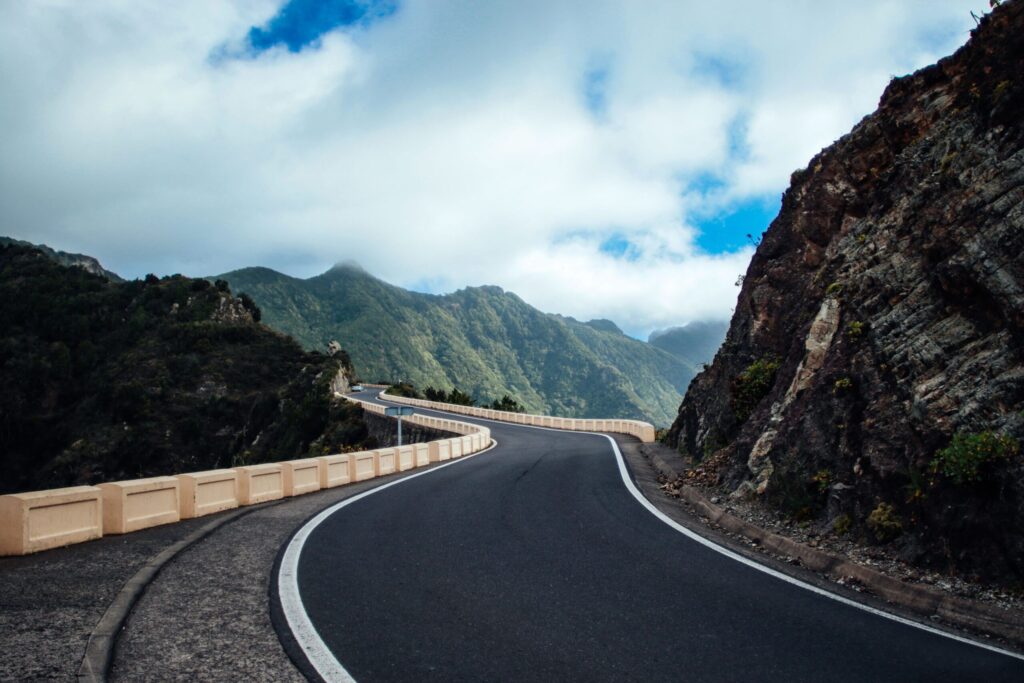 A paved road winding through rocky mountain terrain under a cloudy sky