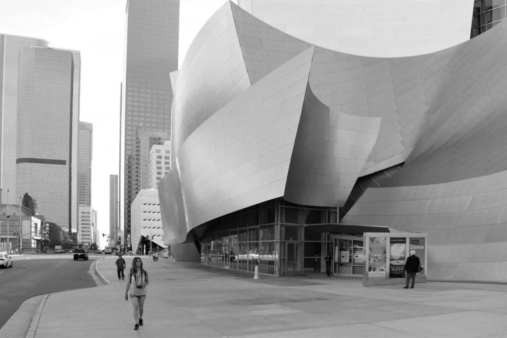 Pedestrians walking past the curved steel walls of the Walt Disney Concert Hall in downtown Los Angeles