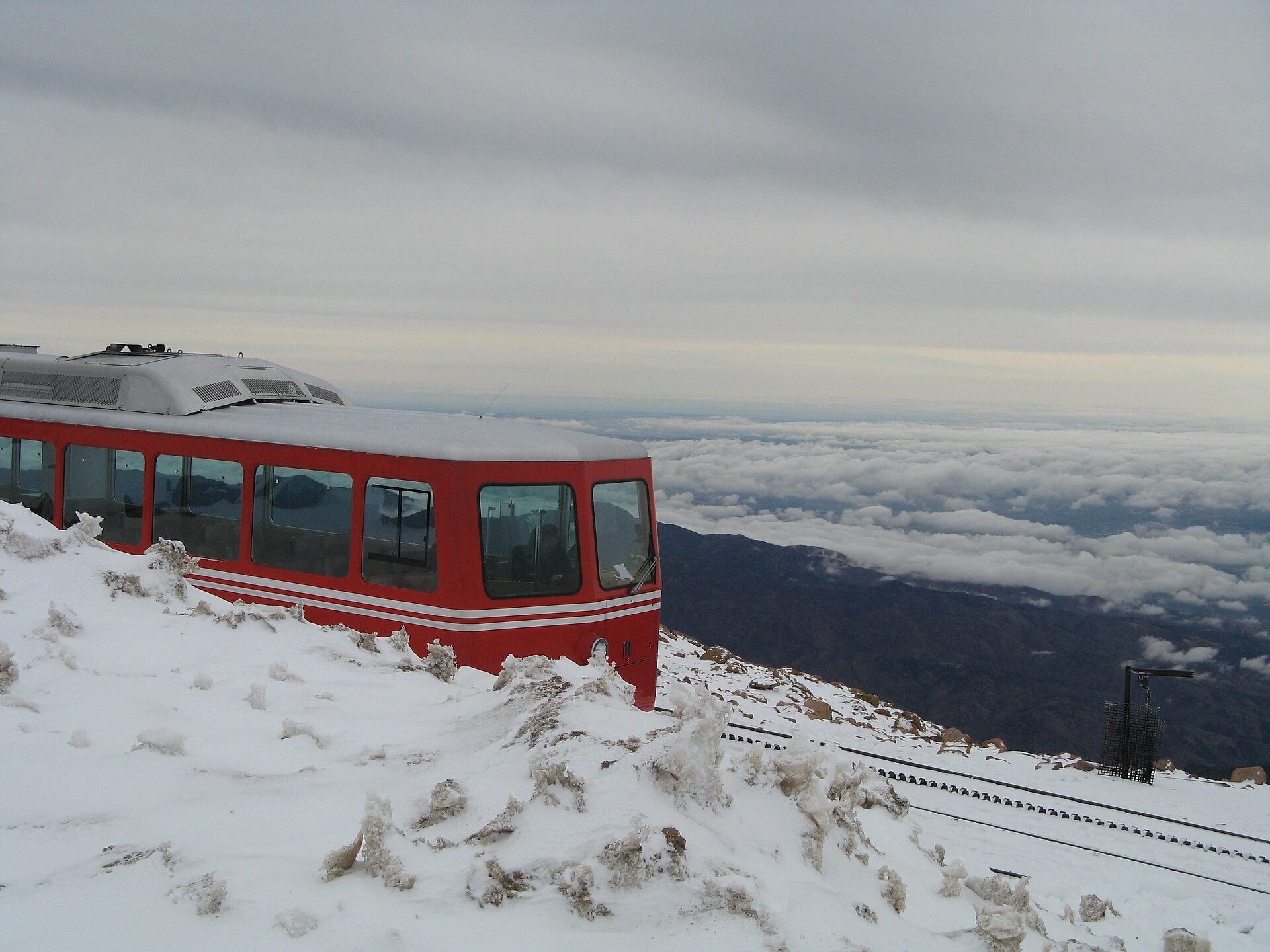 A Pikes Peak Cog Railway train parked at the summit with clouds below