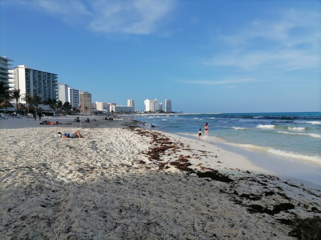 Playa Delfines beach in Cancun with rolling surf and Hotel Zone towers in the distance