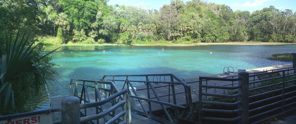 A dock and steps lead into the clear turquoise swimming area at Rainbow Springs State Park