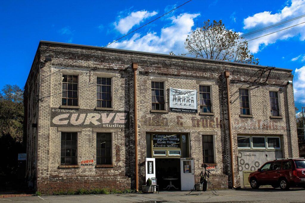 A brick studio building with a mural in Asheville's River Arts District