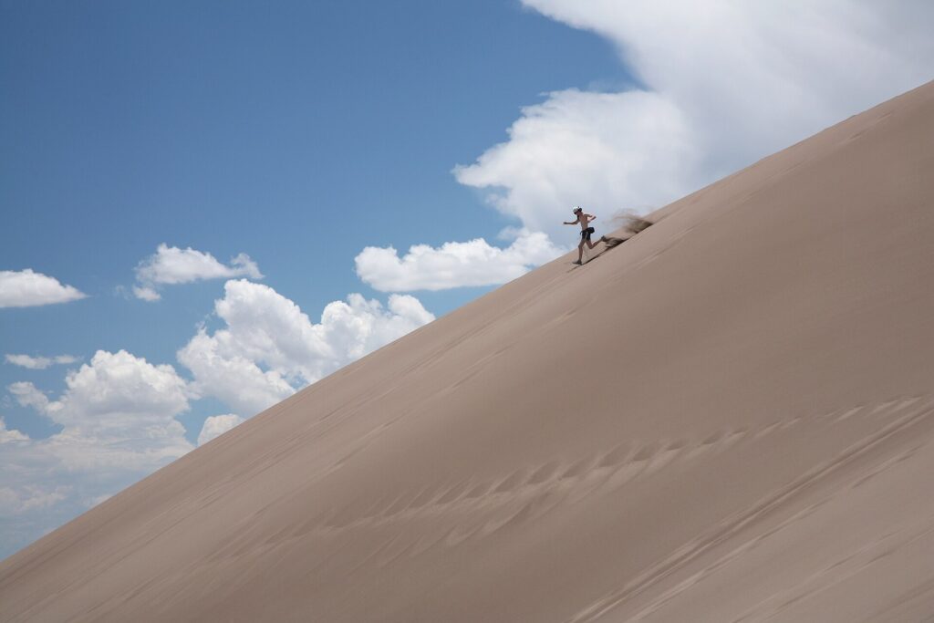 A visitor running down a steep dune face at Great Sand Dunes National Park