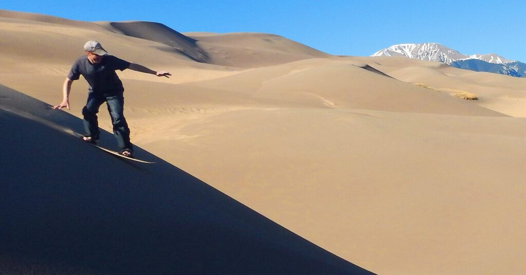 A sandboarder riding down a dune slope at Great Sand Dunes National Park