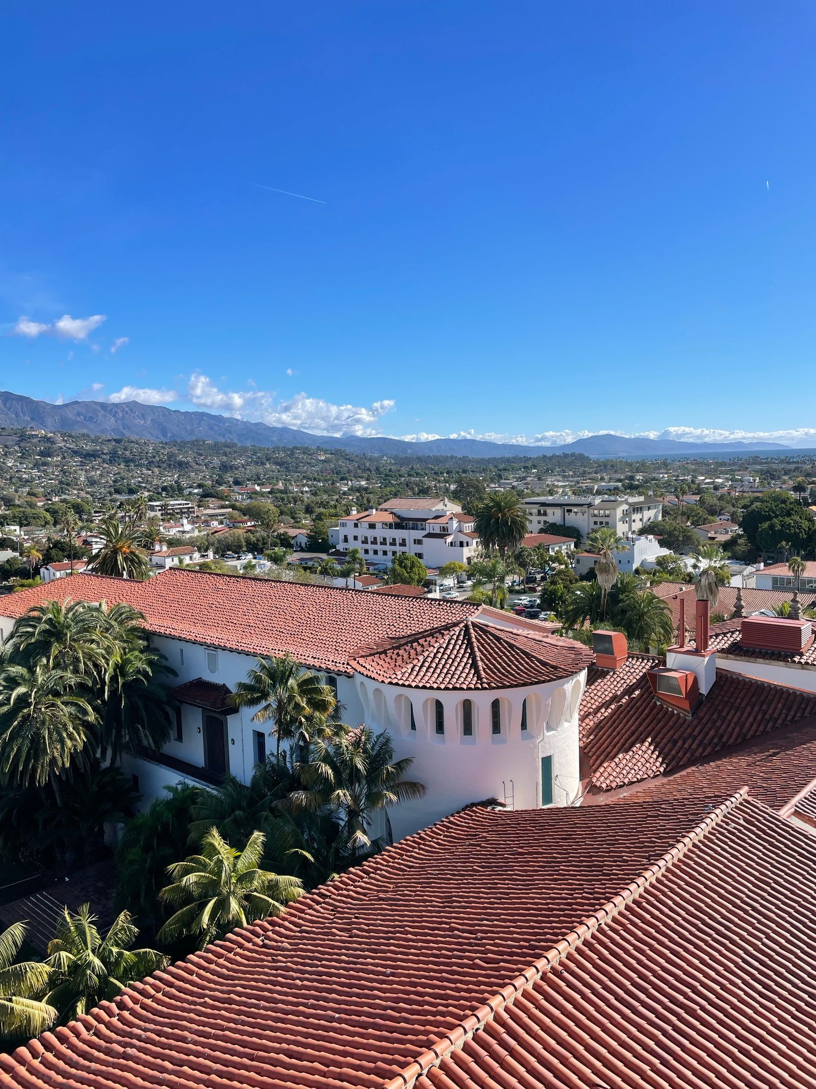 Aerial view of red tile roofs in downtown Santa Barbara with mountains behind