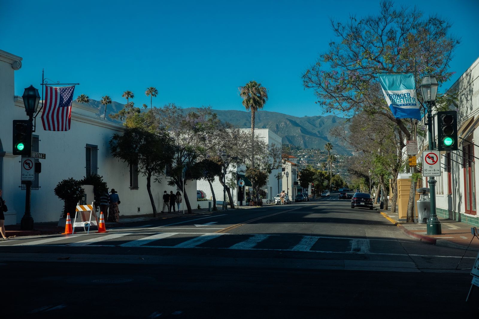 A quiet downtown Santa Barbara street lined with palm trees and mountains in the background